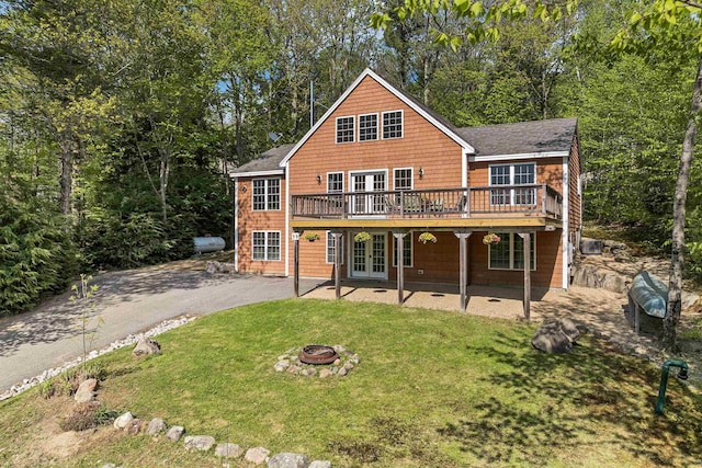 back of property with french doors, a fire pit, a yard, a deck, and asphalt driveway
