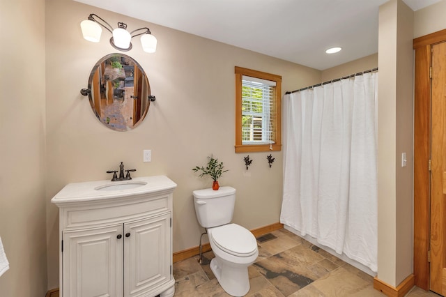 bathroom with baseboards, stone finish floors, toilet, vanity, and a shower with curtain