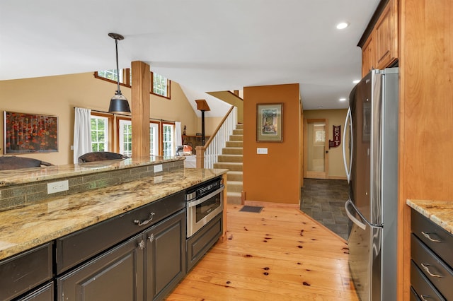 kitchen with stainless steel appliances, light wood-style flooring, recessed lighting, light stone counters, and hanging light fixtures