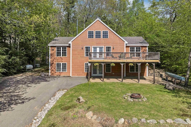 rear view of property featuring an outdoor fire pit, a yard, a deck, and french doors