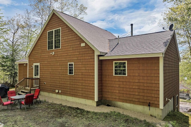 rear view of house with roof with shingles