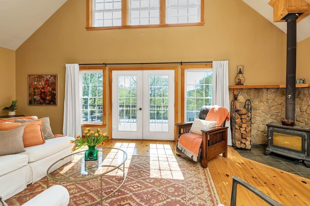 living area with high vaulted ceiling, a wood stove, french doors, and hardwood / wood-style floors