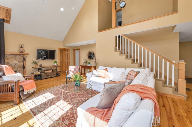 living area featuring hardwood / wood-style flooring, a towering ceiling, stairs, a wood stove, and recessed lighting