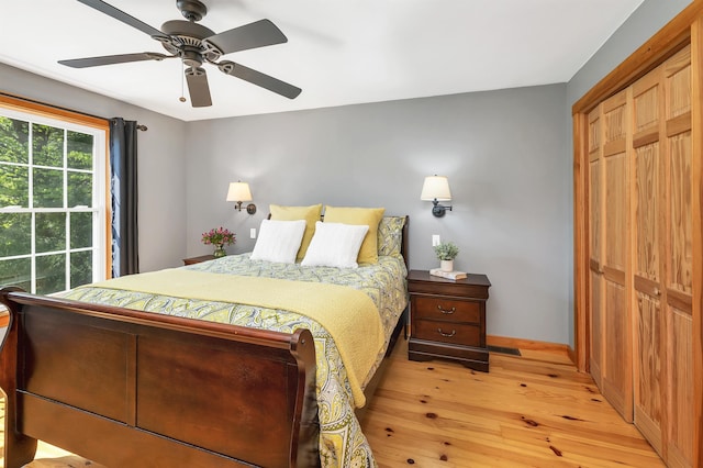 bedroom with light wood-type flooring, baseboards, a closet, and ceiling fan