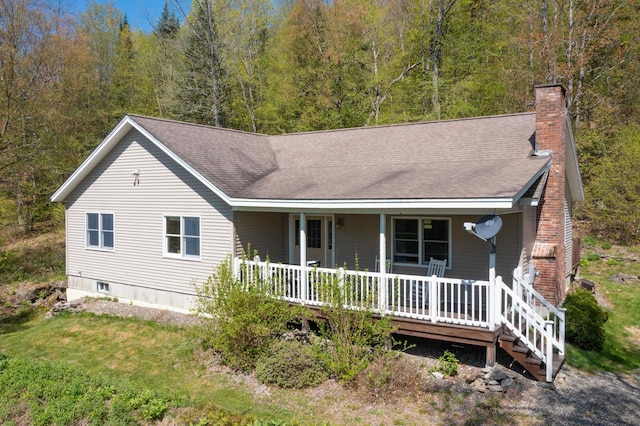 273 Berkshire Rd, Lisbon, NH 03585 - ranch-style house with a porch, a chimney, a shingled roof, and a view of trees