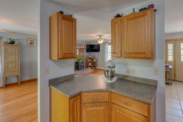 273 Berkshire Rd, Lisbon, NH 03585 - kitchen with a ceiling fan, a wood stove, dark countertops, light wood-type flooring, and baseboard heating