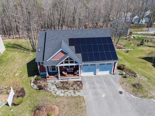 view of front of property with roof with shingles, solar panels, driveway, and a front lawn