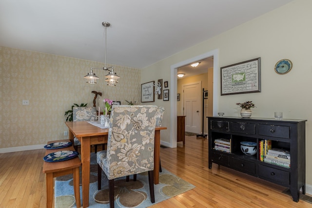 dining room with wallpapered walls, light wood-type flooring, and baseboards