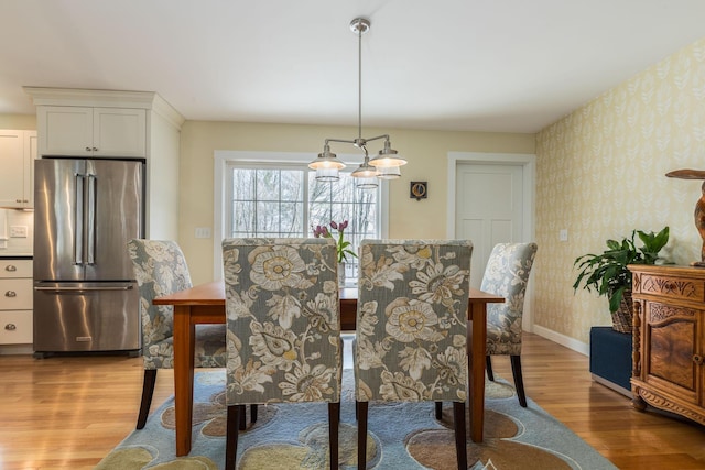 dining space with wallpapered walls, light wood-style floors, and baseboards