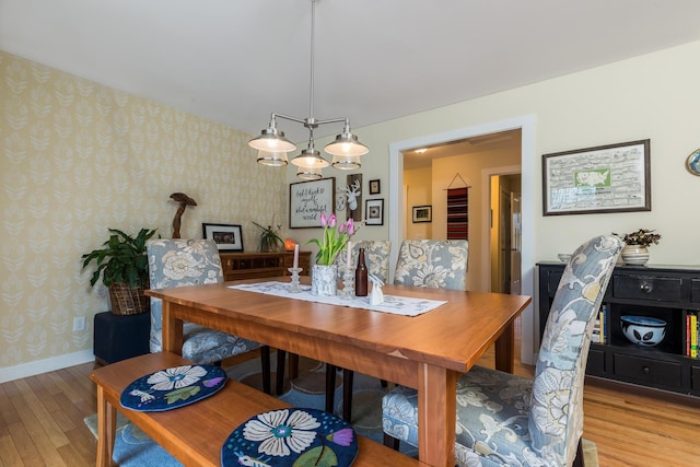 dining area featuring wallpapered walls, wood-type flooring, and baseboards