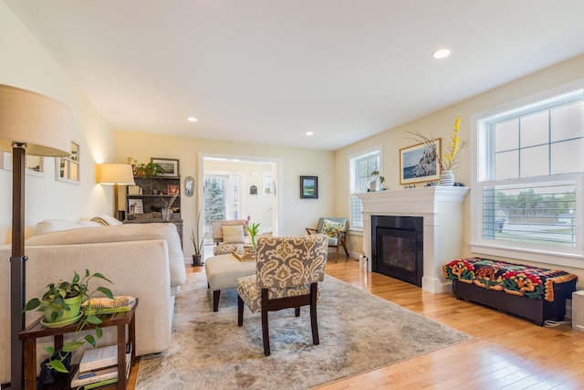 living room with wood finished floors, a glass covered fireplace, and recessed lighting