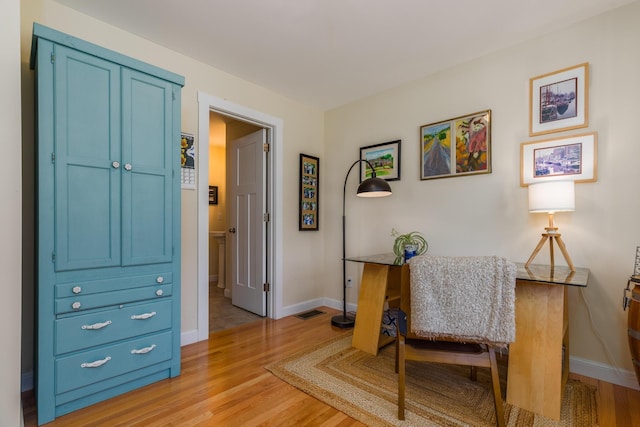 living area with light wood-style floors, baseboards, and an office area