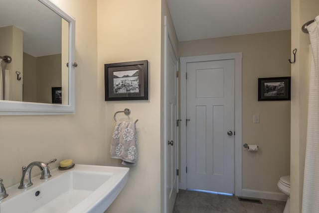 bathroom with a sink, toilet, baseboards, and tile patterned flooring