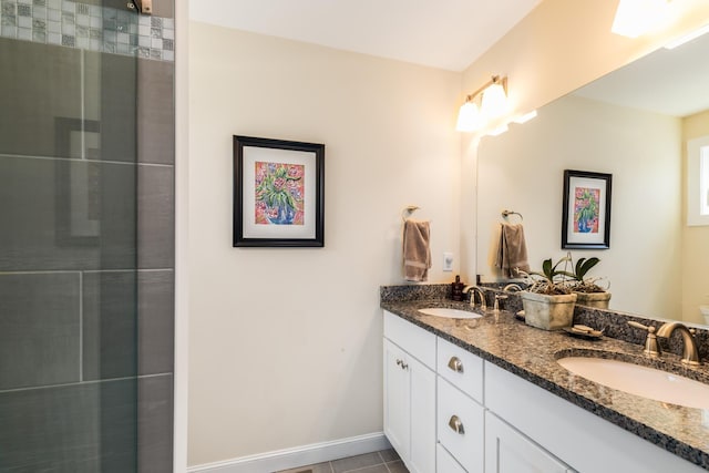 bathroom featuring double vanity, a tile shower, tile patterned floors, and baseboards