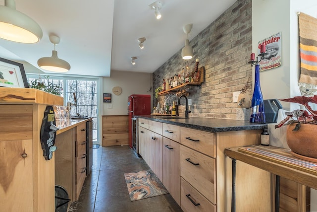 kitchen with a sink, light brown cabinets, dark countertops, brick wall, and open shelves