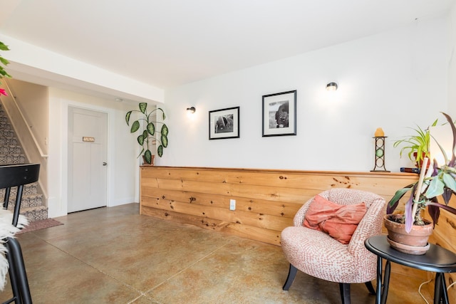 sitting room featuring finished concrete floors and stairway