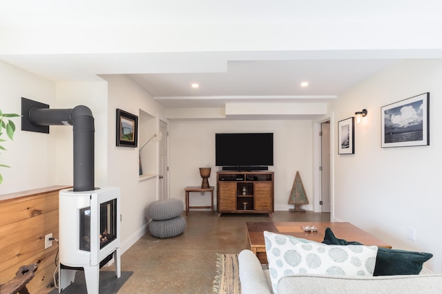 living room featuring a wood stove, finished concrete flooring, recessed lighting, and baseboards