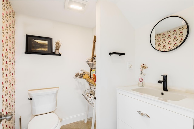 bathroom featuring toilet, vanity, and baseboards