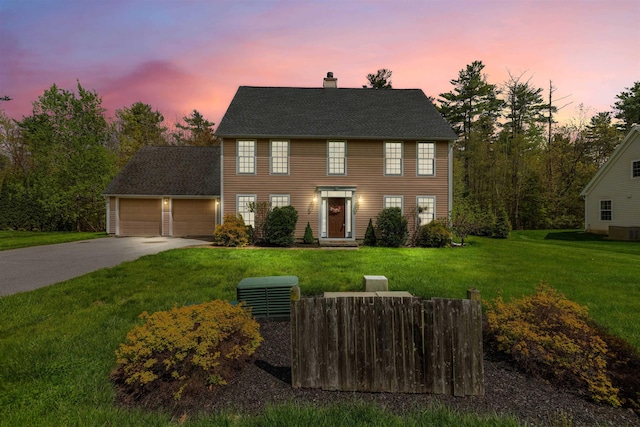 colonial home with driveway, a chimney, an attached garage, a front lawn, and central air condition unit