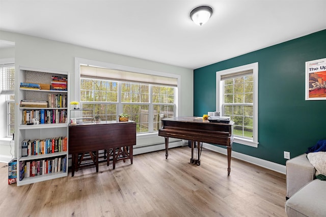 office space with a baseboard heating unit, wood finished floors, and baseboards
