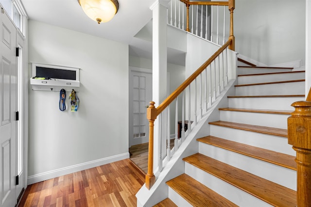 staircase featuring wood finished floors and baseboards