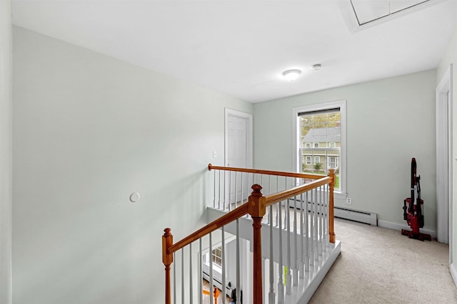 corridor with an upstairs landing, attic access, carpet floors, baseboards, and a baseboard radiator