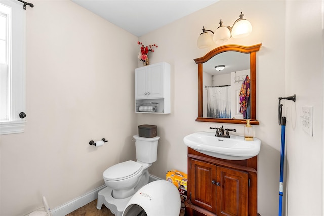 bathroom featuring toilet, vanity, and baseboards