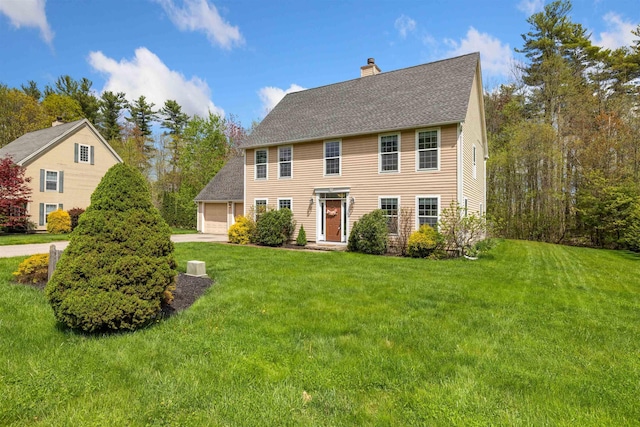 colonial-style house with a chimney, a garage, a front lawn, and a shingled roof