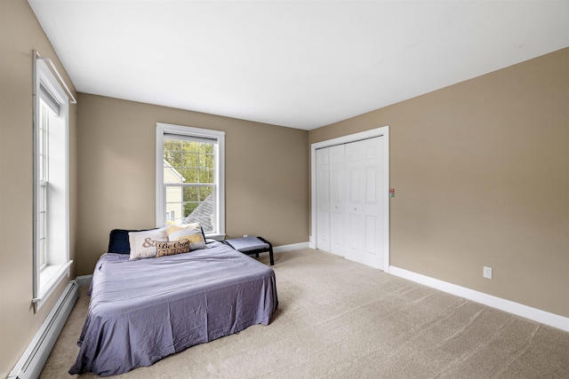 carpeted bedroom featuring a baseboard radiator, baseboards, and a closet