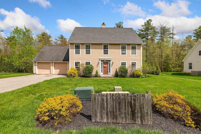 colonial house with a garage, a chimney, cooling unit, concrete driveway, and a front lawn