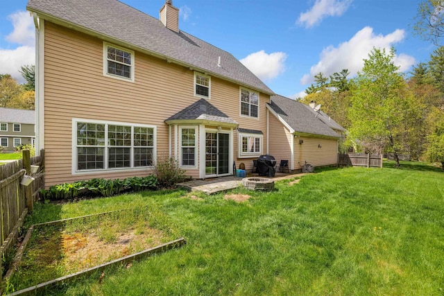 rear view of property with a fire pit, a chimney, and roof with shingles
