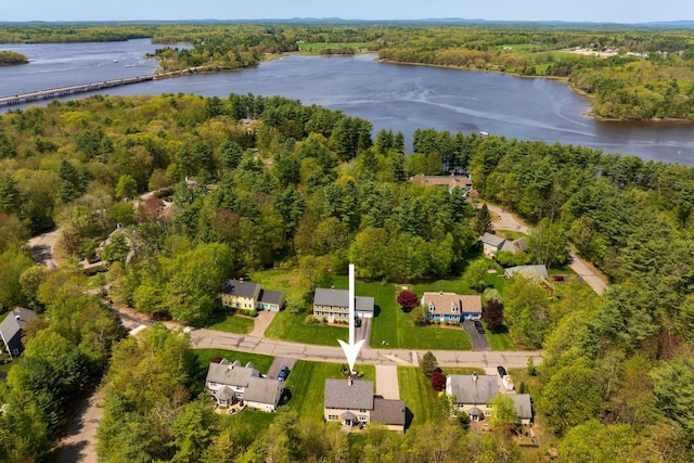 aerial view of property and surrounding area featuring a nearby body of water and a heavily wooded area