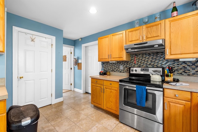 kitchen with electric range, under cabinet range hood, light countertops, decorative backsplash, and light tile patterned floors