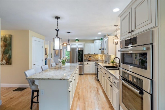 34 Coles Pond Rd, Somersworth, NH 03878 - kitchen featuring appliances with stainless steel finishes, a kitchen bar, light wood-style flooring, a sink, and a kitchen island