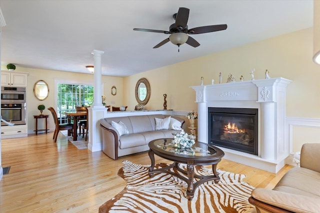 34 Coles Pond Rd, Somersworth, NH 03878 - living area with light wood-style floors, a glass covered fireplace, a ceiling fan, and decorative columns
