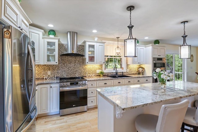 34 Coles Pond Rd, Somersworth, NH 03878 - kitchen with stainless steel appliances, wall chimney exhaust hood, a sink, light wood-style flooring, and backsplash