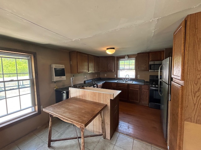 311 Clinton St, Concord, NH 03301 - kitchen with stainless steel appliances, heating unit, a sink, brown cabinetry, and light tile patterned flooring