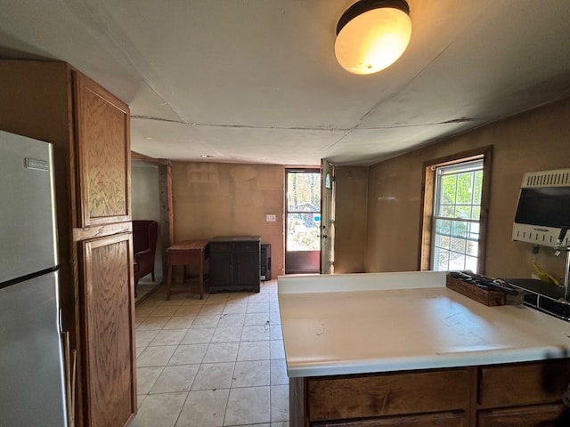 311 Clinton St, Concord, NH 03301 - kitchen featuring freestanding refrigerator, heating unit, light tile patterned flooring, brown cabinets, and light countertops