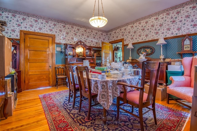 dining room with wallpapered walls and wood finished floors