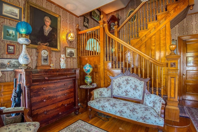living area with wallpapered walls, hardwood / wood-style flooring, and stairway