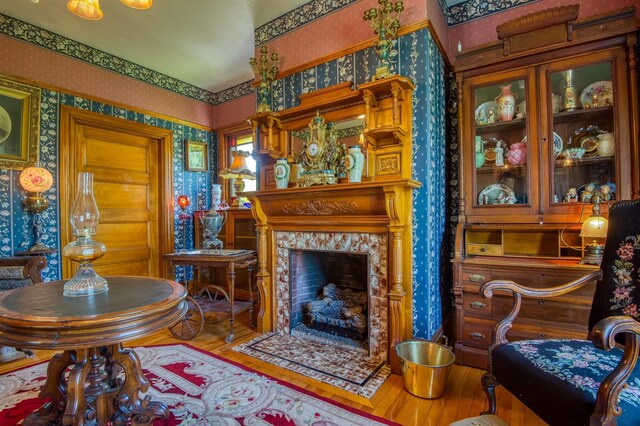 living room with wallpapered walls, wood finished floors, and a fireplace