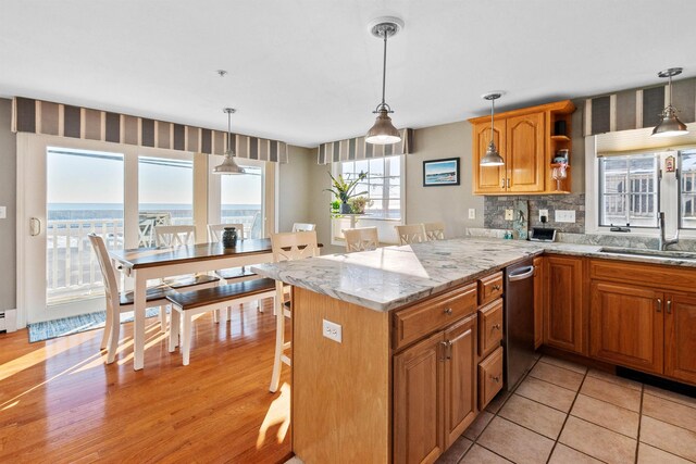 605 Ocean Blvd Unit 1, Hampton, NH 03842 - kitchen featuring a sink, a breakfast bar, decorative backsplash, brown cabinets, and a peninsula