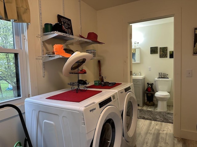laundry area featuring washer and dryer, light wood-style floors, and a sink