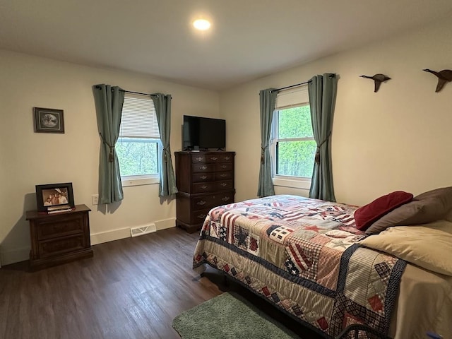 bedroom with multiple windows, dark wood-style floors, and baseboards
