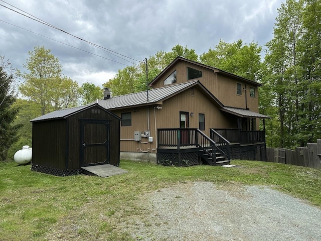 rear view of house with metal roof, a storage unit, a lawn, and an outdoor structure