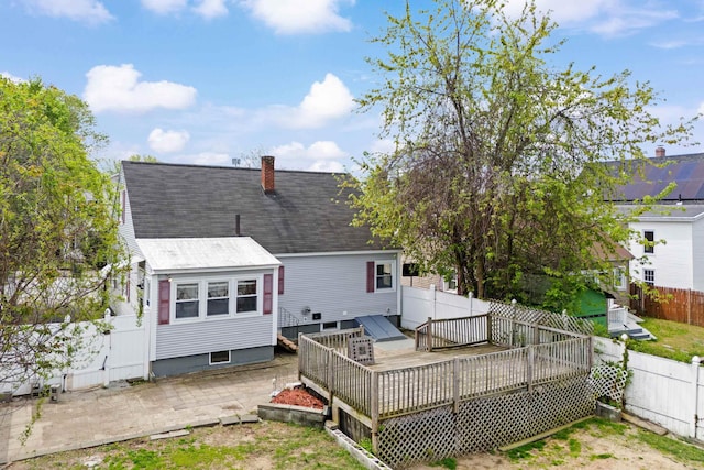552 Dix St, Manchester, NH 03103 - back of house with a fenced backyard, a deck, a chimney, a shingled roof, and a patio area