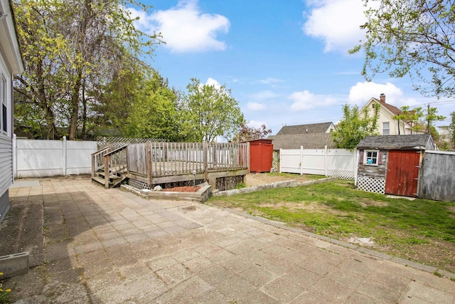 552 Dix St, Manchester, NH 03103 - fenced backyard with a storage unit, a patio, a wooden deck, and an outbuilding