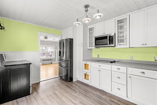 552 Dix St, Manchester, NH 03103 - kitchen featuring stainless steel appliances, radiator, white cabinetry, wood finished floors, and a wainscoted wall