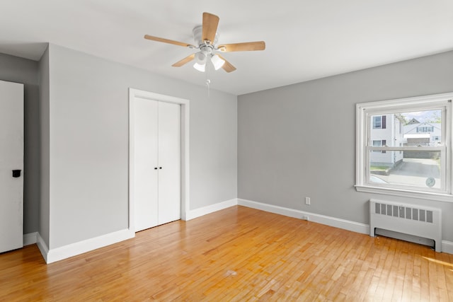 552 Dix St, Manchester, NH 03103 - unfurnished bedroom with radiator, light wood-style floors, baseboards, a closet, and a ceiling fan