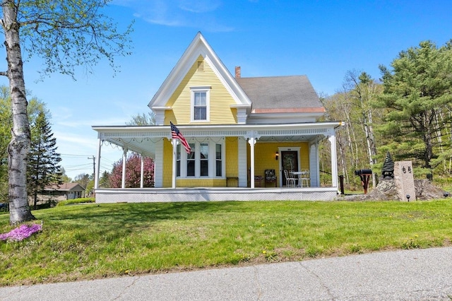 view of front of home with covered porch, a front yard, and a chimney